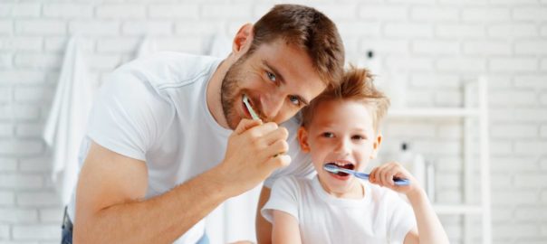 Father and child practicing good home dental habits brushing teeth