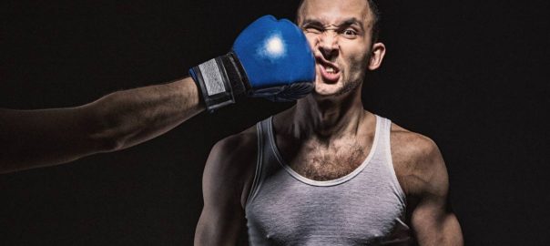 Man getting hit in the face by another man with a boxing glove